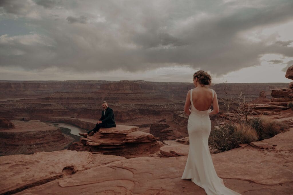 Adventurous elopement couple at Dead Horse State Park in Moab Utah at Sunset with moody cloudy desert skies